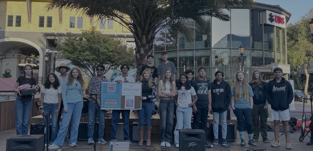 Young volunteers from Bye Bye Kid's Cancer holding signs at a talent show